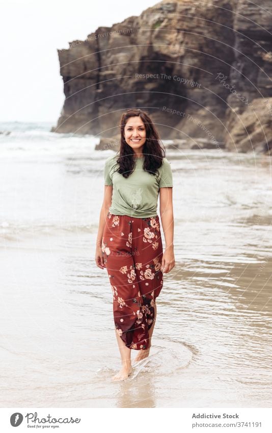 Smiling woman on beach in summer wet seashore walk water cliff seaside female relax travel tourism traveler coast ocean rocky nature happy vacation lady holiday