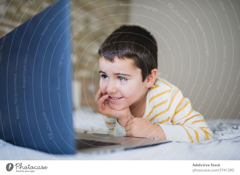 Little kid using laptop at home little gadget boy browsing bedroom child surfing internet addict device online lifestyle male preschool connection focus watch