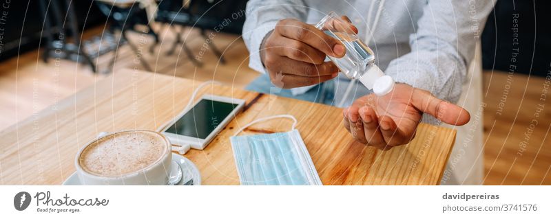 Unrecognizable man disinfecting his hands with hydroalcoholic ge hydroalcoholic gel pouring gel bottle disinfecting hands covid-19 hand rub coronavirus cafe