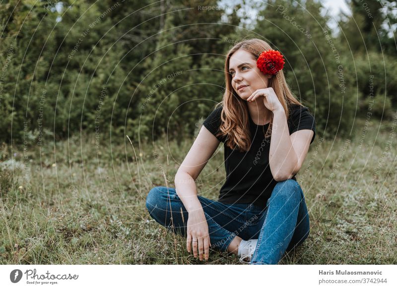 Young beautiful woman with flower in hair sitting in nature attractive background beauty blonde caucasian cute fashion female happiness happy lifestyle