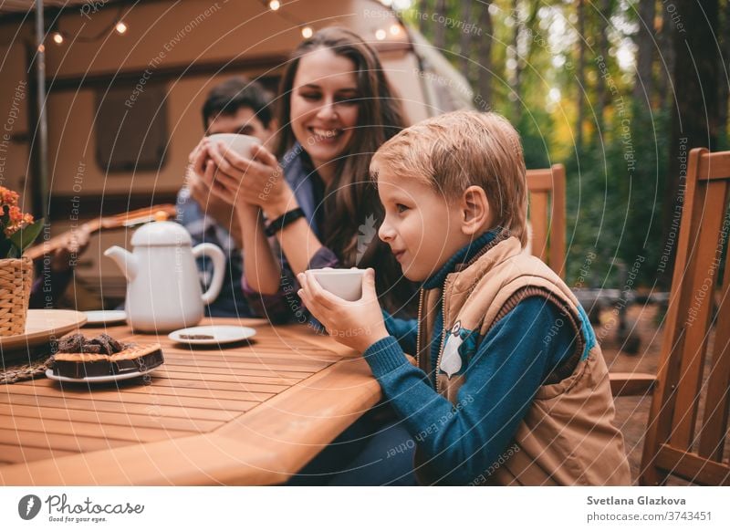 Happy family on a camping trip relaxing in the autumn forest. Camper trailer. Fall season outdoors trip fall nature father mother together fun happy people park