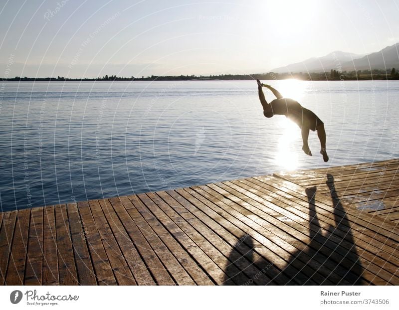 A young man jumping into the water at lake Issyk Kul in Kyrgyzstan summer freedom youth issyk kul kyrgyzstan pier joy