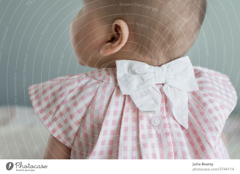 baby girl wearing pink gingham dress with bow infant Child 0 - 12 months Infancy childhood Small Cute candid Bow Buttons Hair and hairstyles Baby hair Girl