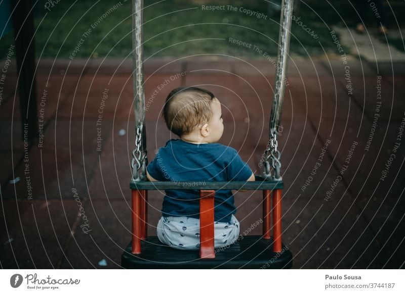 Rear view child playing on the swing Swing Playground Child Children's game childhood Authentic Copy Space bottom Toddler Leisure and hobbies Day Colour photo