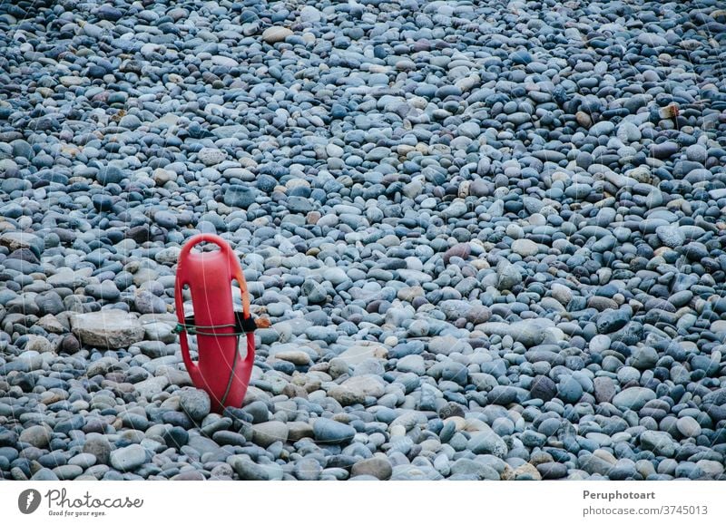 Red plastic buoyancy aid in the sand on lonely beach background torpedo water summer sun guard coast safety tube rescue lifeguard red equipment float protection