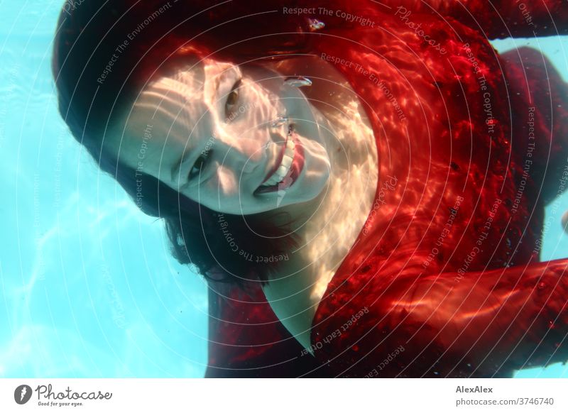 Underwater portrait of a young woman in a red dress girl Young woman Woman 18-25 years already Athletic smile Laughter Red-haired Dark-haired fit Dive be afloat