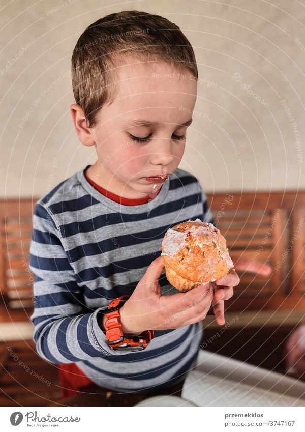 Boy enjoying eating sweet tasty cupcake that you she made herself child cookie dessert happy happiness cheerful small little kid unhealthy sugar food boy home