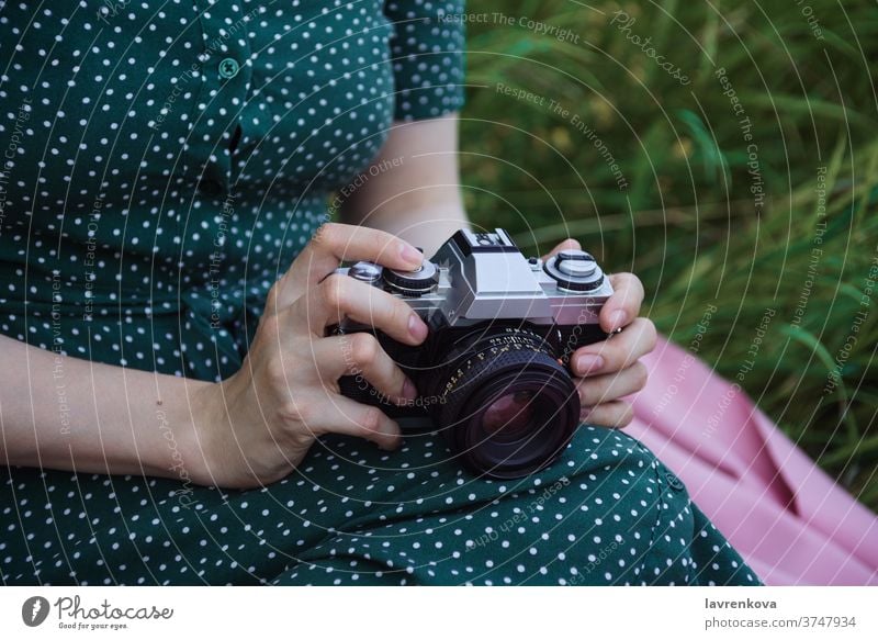 Closeup of woman's hands holding film vintage camera closeup female faceless photographer professional dress pictures outdoors grass