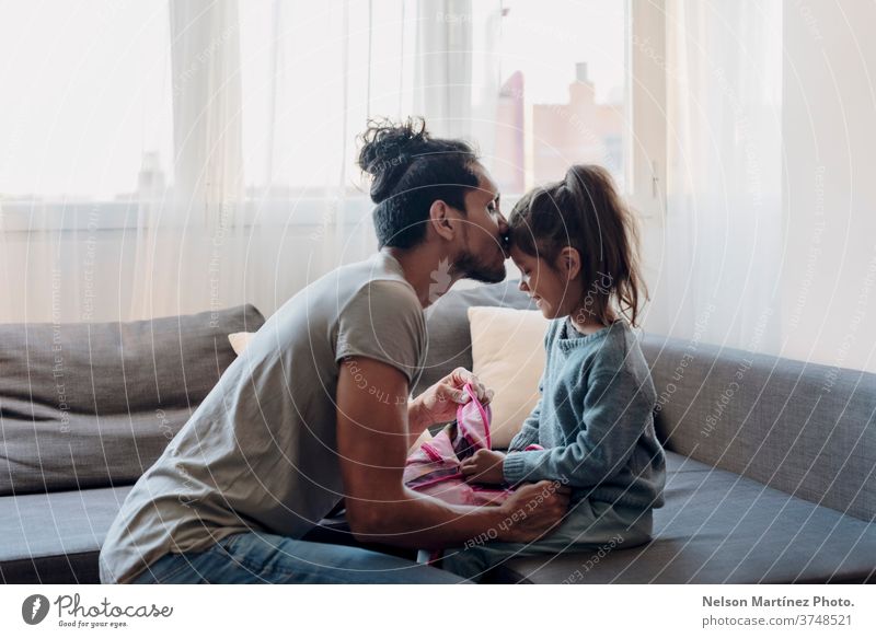 Father getting his daughter ready for back to school. He is kissing her in the fronthead. person student education backpack people cute children holding blond