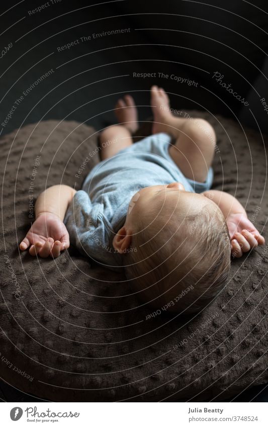 sleeping newborn baby lying on pillow wearing gray onesie infant child 0 - 12 months infancy childhood small cute relaxed candid cheeks baby hair window light