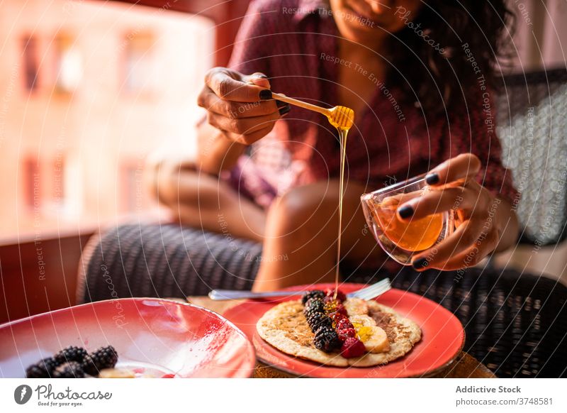 Anonymous woman eating healthy pancakes for breakfast plate sweet fresh tasty fruit delicious raspberry honey organic food enjoy blueberry gluten free snack