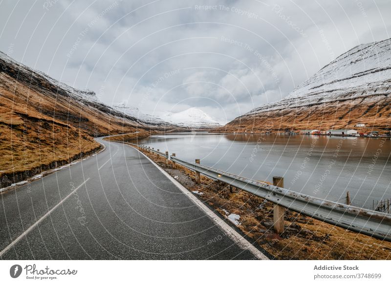 Wet mountain road on Faroe Islands winter wet winding spectacular roadway slope river cold faroe islands landscape rock picturesque water weather dry grass