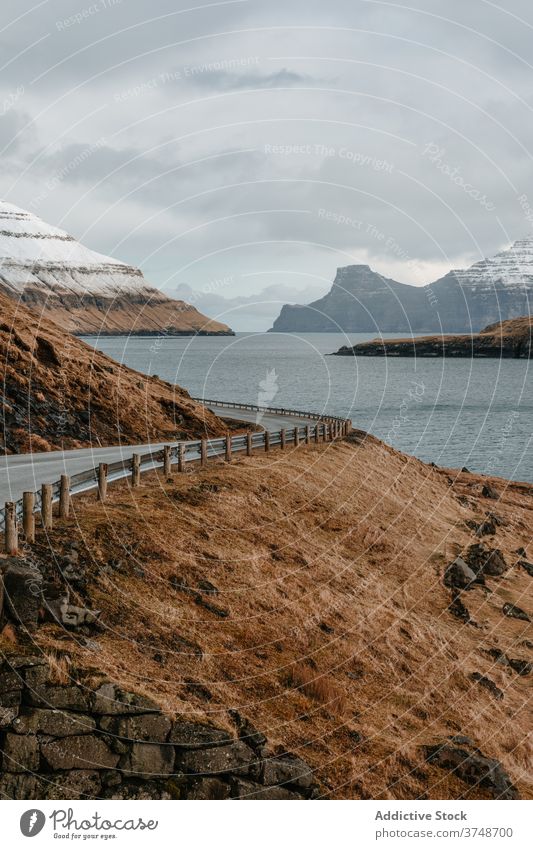 Wet mountain road on Faroe Islands winter wet winding spectacular roadway slope river cold faroe islands landscape rock picturesque water weather dry grass