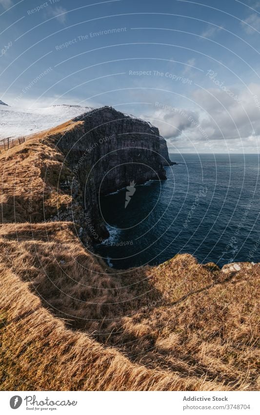 Rocky cliff near sea on Faroe Islands rock seascape winter snow season cold steep terrain faroe islands rocky scenery majestic coast shore water sky calm