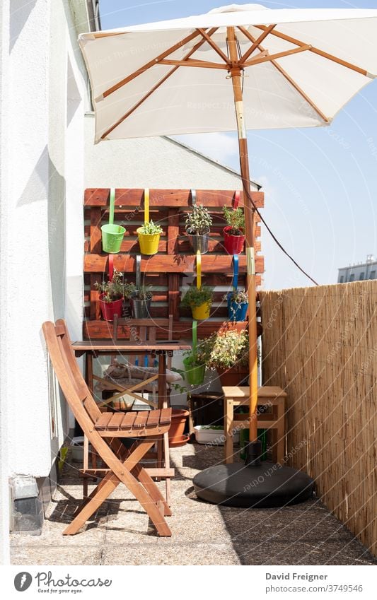 Small area of urban gardening in summer in the city terrace balcony colorful plants sunshine chair relaxation pot pots parasol sunshade pallet upcycling small