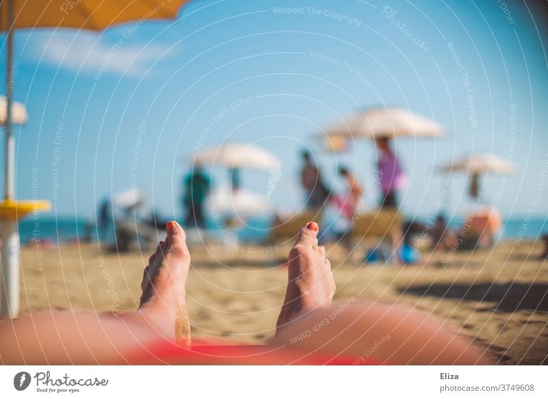 Woman lying relaxed on the beach on vacation Beach Lie sunny Summer vacation feet Ocean beach holiday Relaxation Sunbathing go away parasols sunbathing