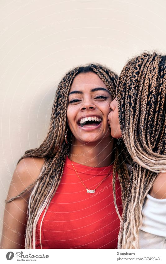 Lovely African American Sisters kiss giving a kiss sisters african girls front view looking at camera siblings braids african american street attractive young