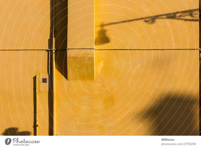 On a yellow house wall different shadows meet in the evening Yellow Wall (building) Evening evening light built Shadow Lantern projection Street conduit