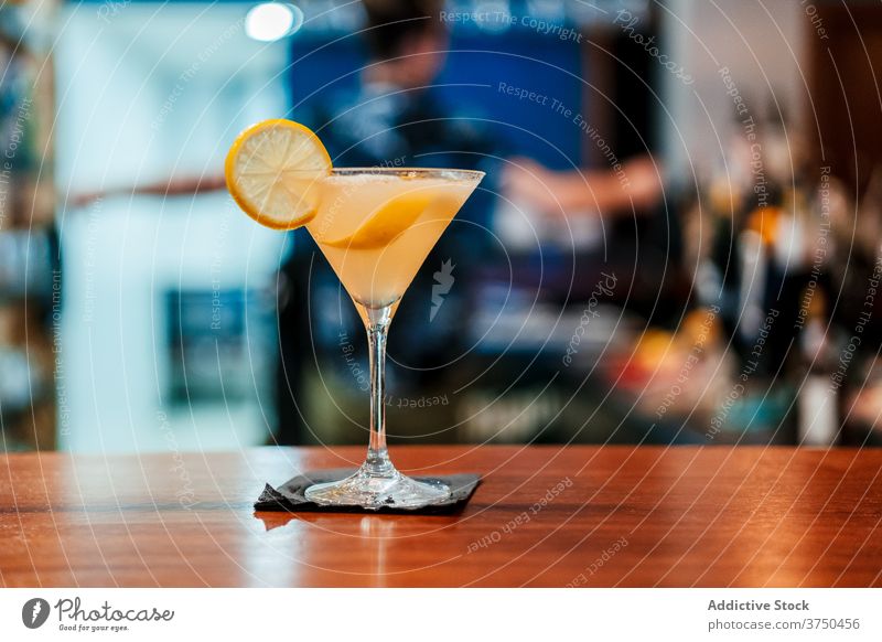 Glass of refreshing cocktail on counter delicious alcohol lemon garnish bar refreshment glass crystal pub tasty citrus wooden cold serve liquid drink fruit