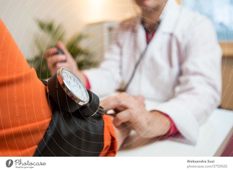 Doctor measuring blood pressure of female patient in hospital office. Sick senior woman having a doctor appointment. Close up care support old people hand