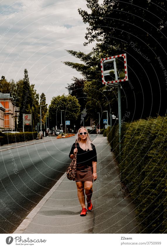 Young woman strolls through the streets of Überlingen on Lake Constance Blonde long hairs amble Street Green Town Sky Clouds Summer Sun sunglasses Dress Fashion