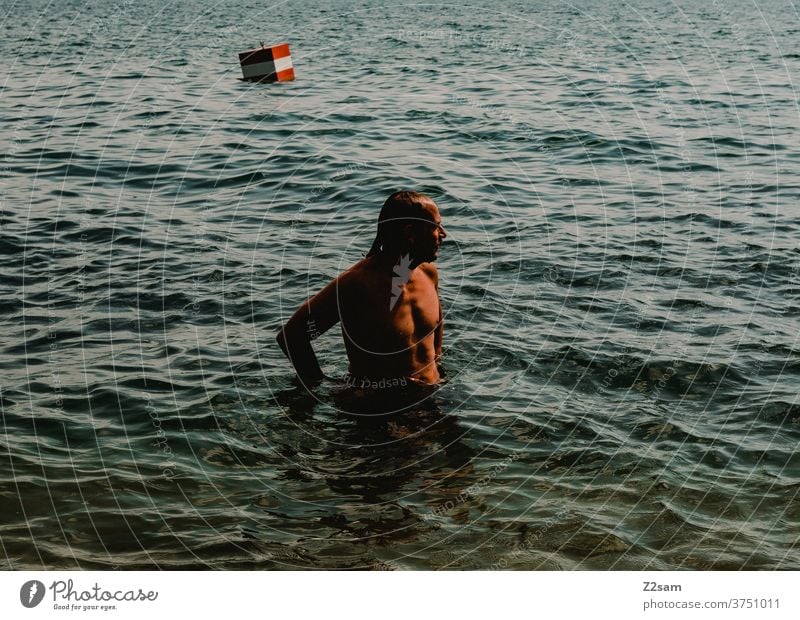 Young man bathes in the lake Man Summer Sun Shadow Light Water Lake Body of water Turquoise Buoy Swimming & Bathing Reflection Vacation & Travel Relaxation