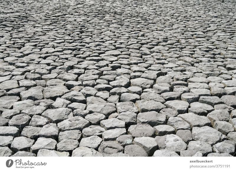 cobblestone background with uneven natural stone pattern rock texture paving surface pavement gray abstract backdrop cobbled rocks blocks nobody perspective