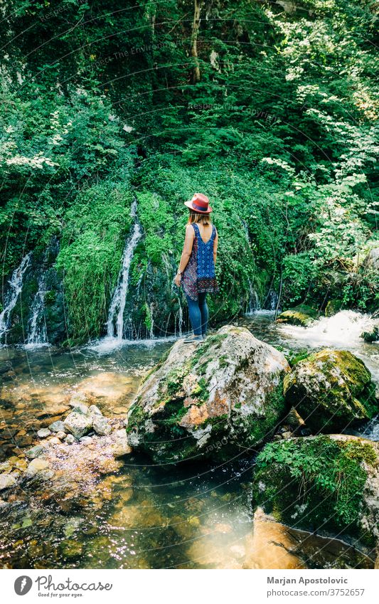 Young female nature explorer enjoying by the waterfalls adventure beautiful cascade casual caucasian discover discovery flow flowing forest fresh girl green