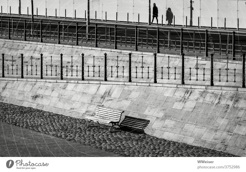 A woman goes away at the Spreebogen in Berlin, a bank remains empty Promenade Town Bench Street Handrail Shadow Light diagonal firecracker Pole Woman Passer-by