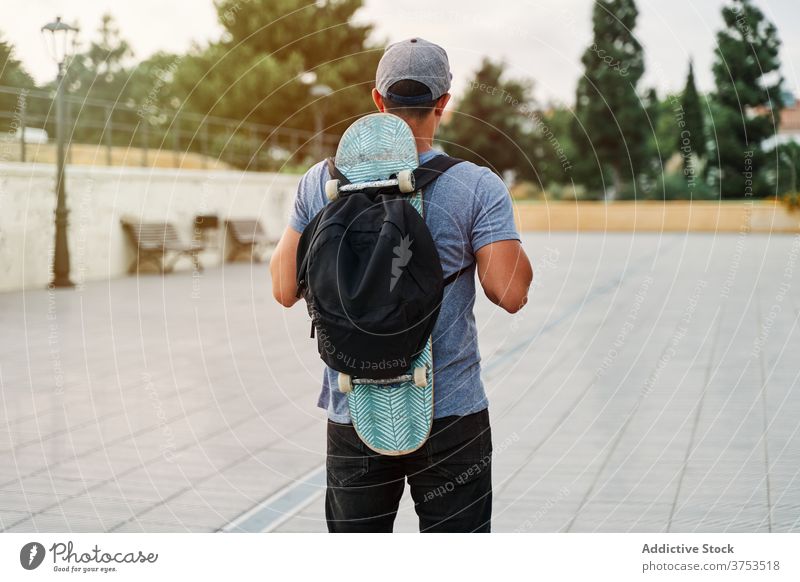 Unrecognizable man with skateboard and backpack in city skater street urban style skill hobby male old hipster cool stand town trendy modern contemporary summer