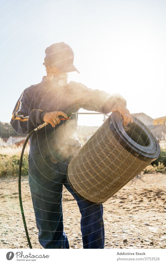 Farmer cleaning detail of agricultural vehicle farmer machine filter maintenance hose dust dirty repair spray agriculture respirator protect hydraulic farmland