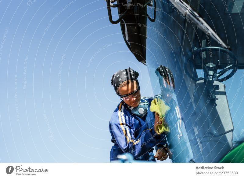 Woman cleaning window of agricultural machine woman farm agriculture machinery combine harvest cleanse female worker busy uniform modern occupation rural area