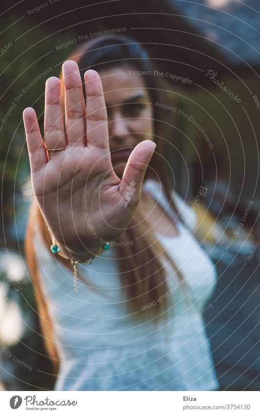 A young woman symbolizes stop by stretching out her hand in front of her. No means no. holds Woman Young woman no means no Defensive Cancelation Emotions Signal