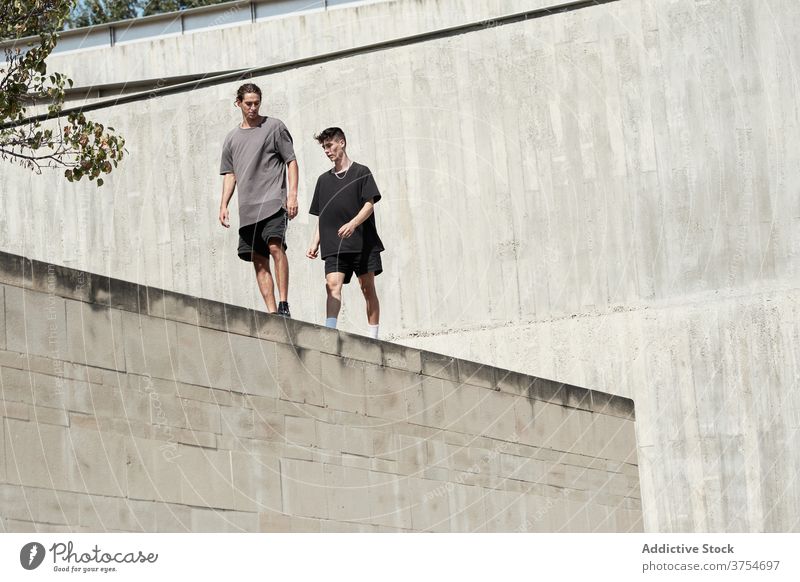 Young men standing on roof of building in city parkour trick prepare freestyle urban young skill ready concrete border extreme activity friendship together