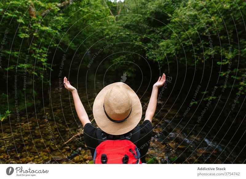 Traveling woman with backpack near pond in woods carefree traveler freedom enjoy forest lake vacation summer female tourist hat calm trip journey wanderlust