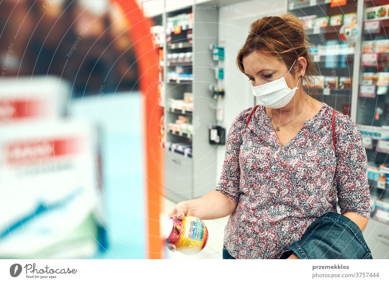 Woman shopping at pharmacy, buying medicines, wearing face mask during pandemic coronavirus outbreak woman chemist covid-19 cover standing town female care