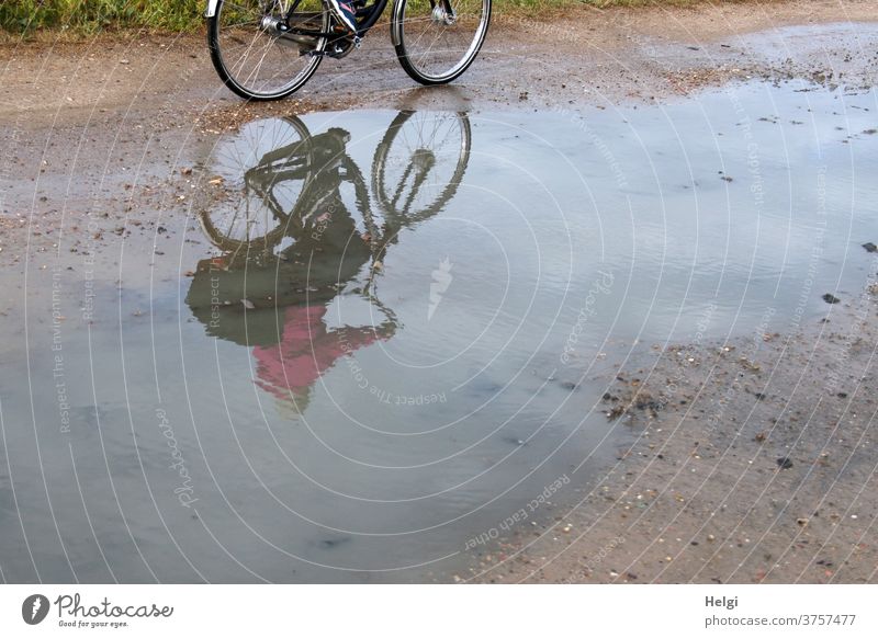 Cyclist mirrored in a large puddle on a dirt road | dynamic Bicycle cyclist reflection Puddle Nature Environment off the beaten track Exterior shot Reflection