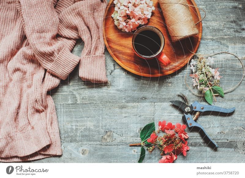 autumn or summer garden table top view with cozy sweater, coffee, dried hydrangea flowers and garden pruner background cup morning spring wooden natural nature