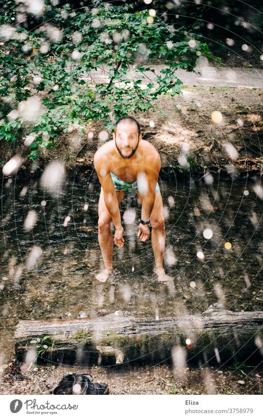 Man in bathing suit stands in stream and splashes with water Water Inject River Wet Drops of water Human being splashing Brook Swimming trunks fun Refreshment