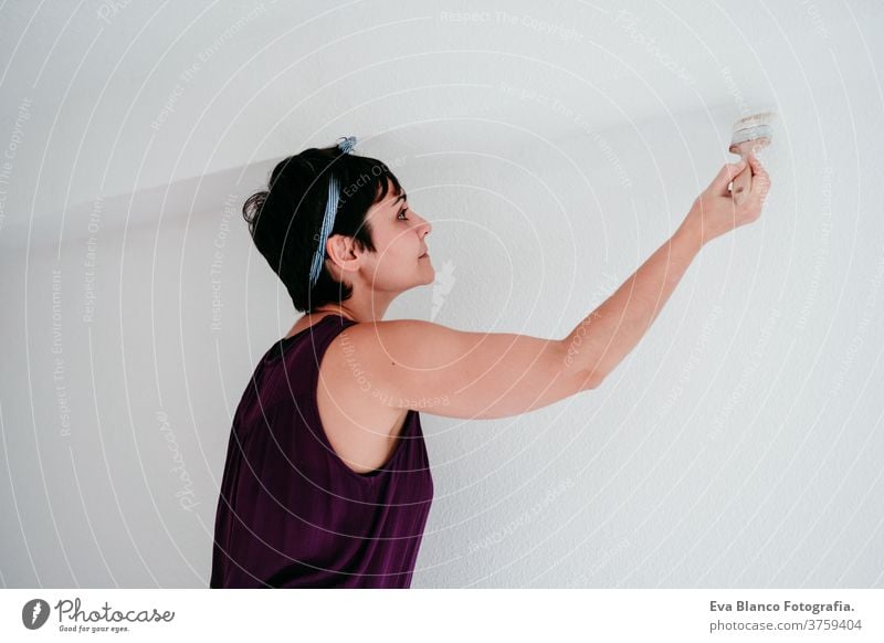 happy caucasian woman painting the room walls with white color. Do it yourself and new home concept house brush young new house painter bricolage america solo