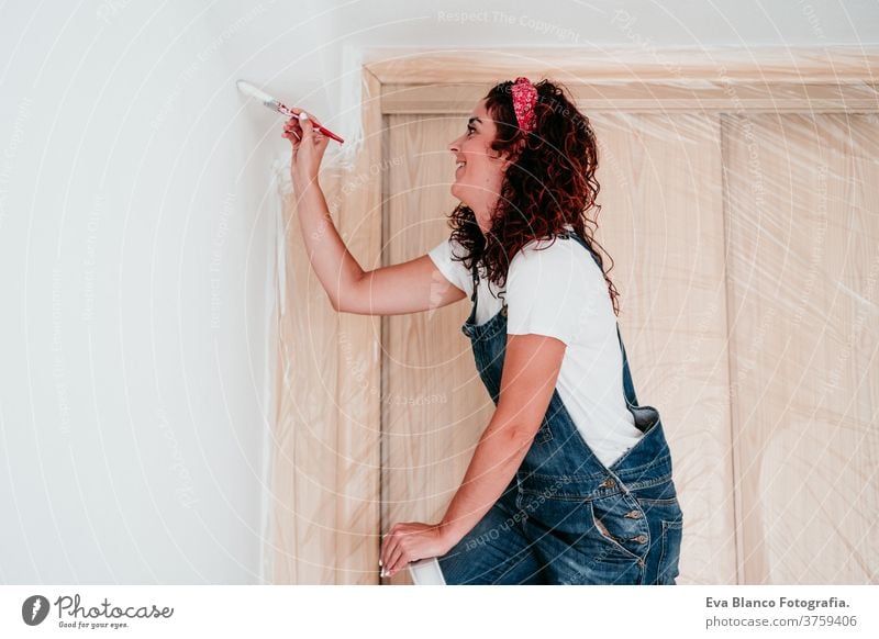 happy caucasian woman painting the room walls with white color. Do it yourself and new home concept house brush young new house painter bricolage america solo