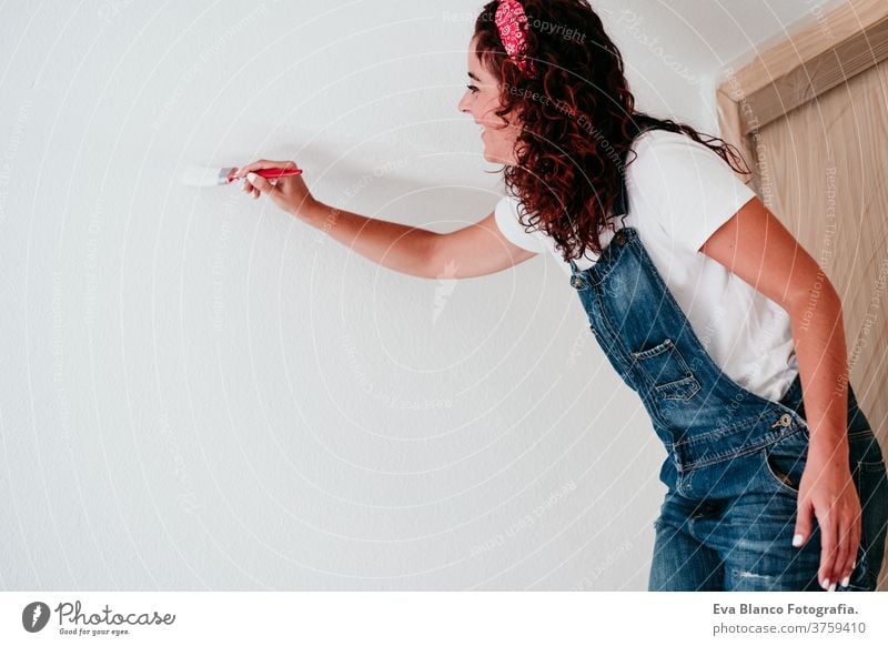 happy caucasian woman painting the room walls with white color. Do it yourself and new home concept house brush young new house painter bricolage america solo