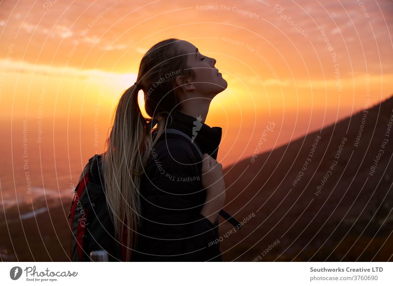 Profile view of young woman with eyes closed on top of mountain at sunset outdoors adventure nature person travel one summer leisure activity backpack