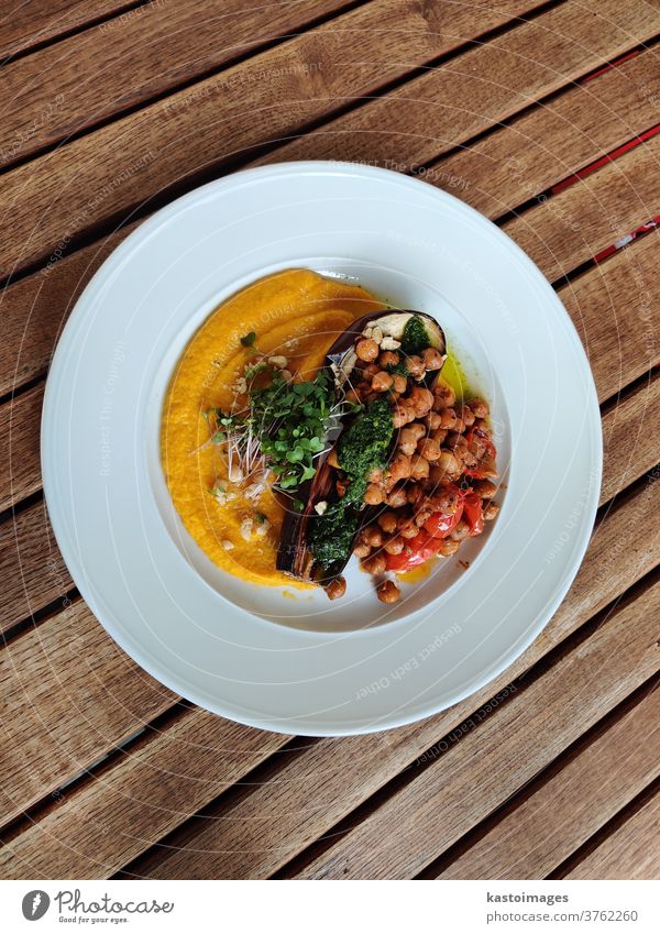 Healthy vegan dish made of eggplant, chickpeas and zucchini puree, pesto, cherry tomatoes and fresh herbs. pesto chery tomatoes meal healthy cuisine decoration