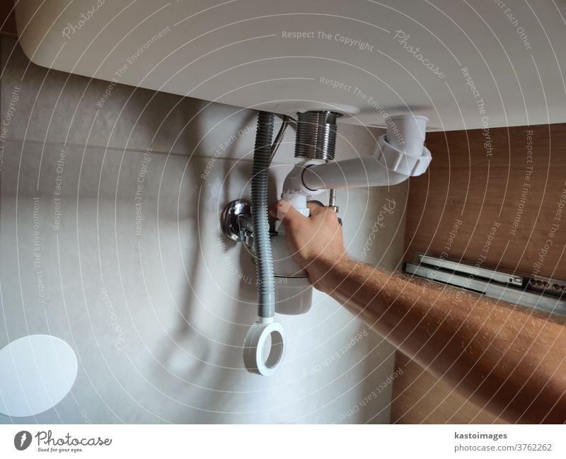 Plumber assembles a siphon under the bathroom sink plumber assembling tube valve Bathroom Sink Tap Interior shot craftsman handicrafts seal Water Metal