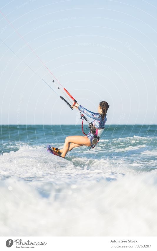 Female kite surfer riding on board in sea woman ride wave splash summer professional female swimsuit fit ocean recreation holiday swimwear surfing surfboard