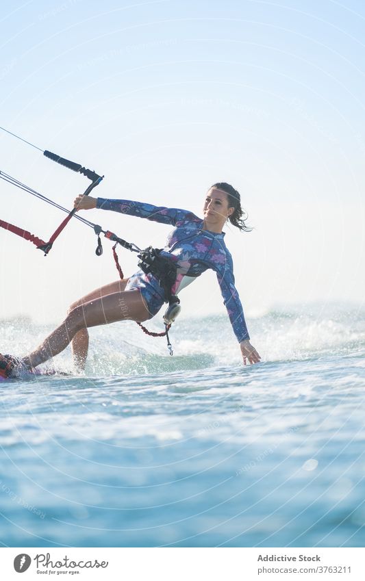 Female kite surfer riding on board in sea woman ride wave splash summer professional female swimsuit fit ocean recreation holiday swimwear surfing surfboard