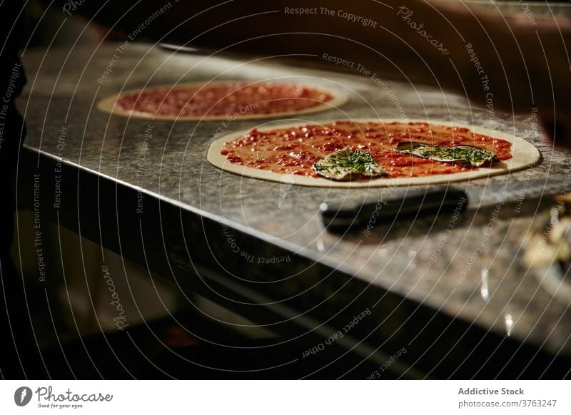 Preparation of pizza with tomato sauce dough prepare food cook kitchen ingredient raw leaf herb thin restaurant marble cuisine meal culinary italian lunch