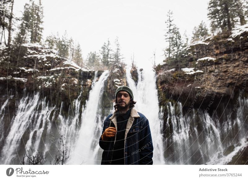 Male traveler on waterfall in snowy mountainous forest in winter day man flow nature person landscape pool male cold stream scenic picturesque scenery tourism