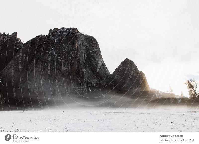 Anonymous person in peaceful view of mountains in winter blizzard valley highland snow cloudy nature rock landscape usa united states america scenic season